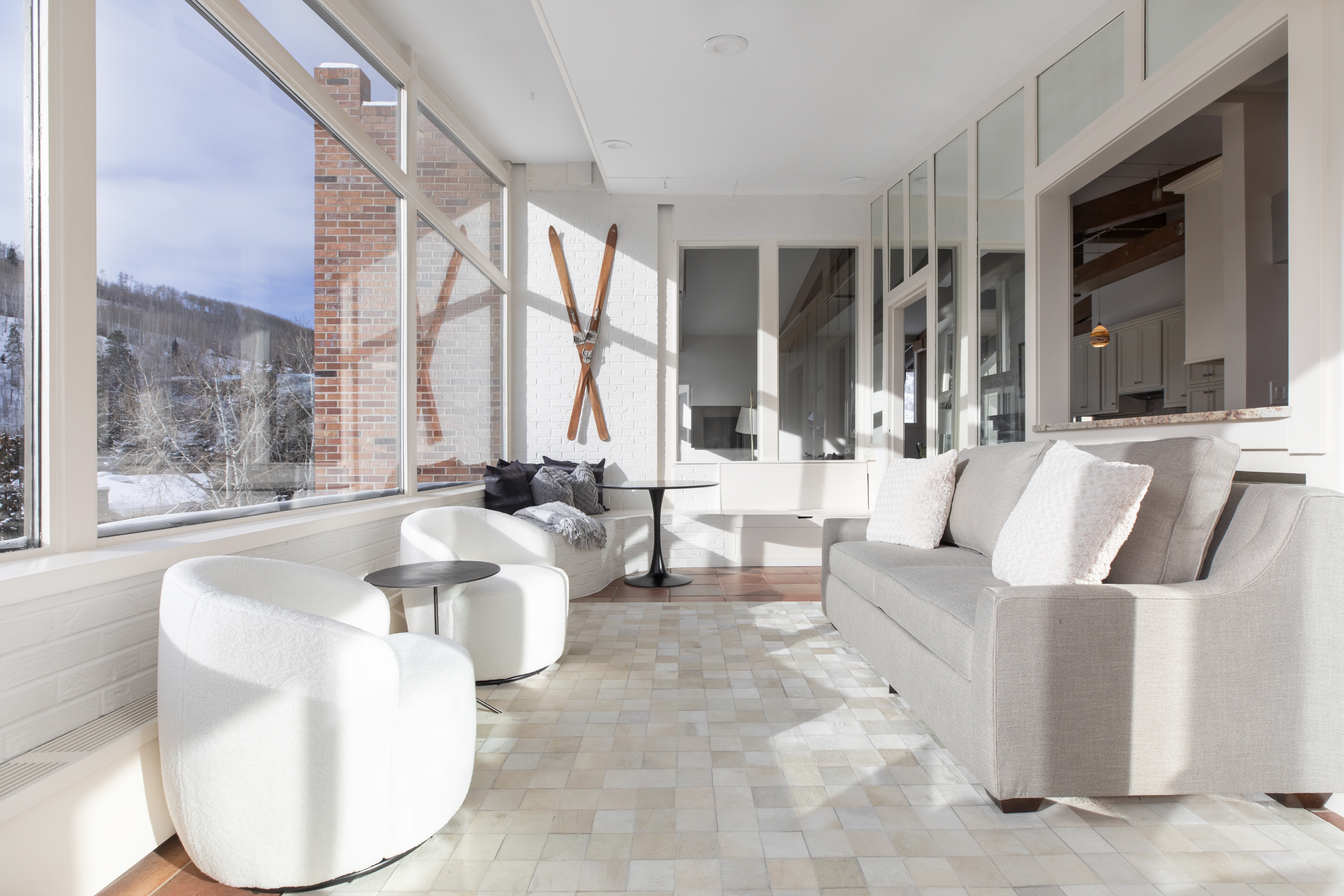 A bright and airy lounge with a seating area and large windows overlooking a snowy landscape.